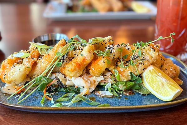 A picture of customers enjoying a lazy afternoon with food and drinks on the Kilmorey Patio on the bank of Waterton Lake.
