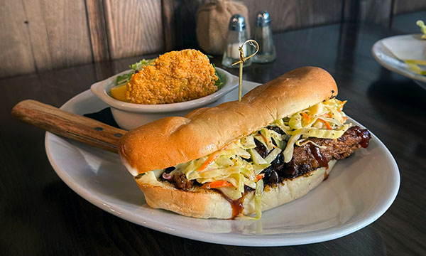 An image of the House Smoked Brisket Sandwich served with a caesar salad.